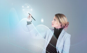 A woman in a business suit is using a stylus to draw on a digital screen in a modern office setting.